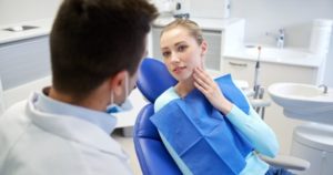 woman at the dentist, holding jaw in pain