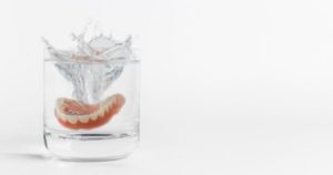 dentures dropped in a glass of water