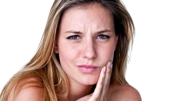 Woman holding jaw in pain.