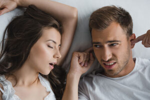 Young man plugging his ears from snoring partner